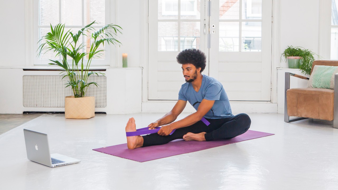 Man using a yoga strap in a yoga forward fold