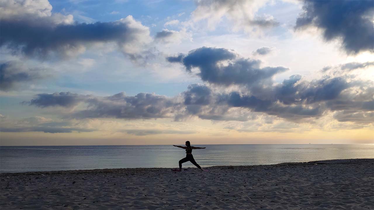 woman doing yoga on a beach in the evening